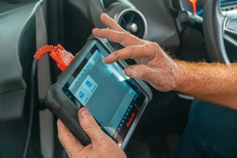 Araç içinde elektronik arıza tespit cihazını kullanan teknisyenin elleri